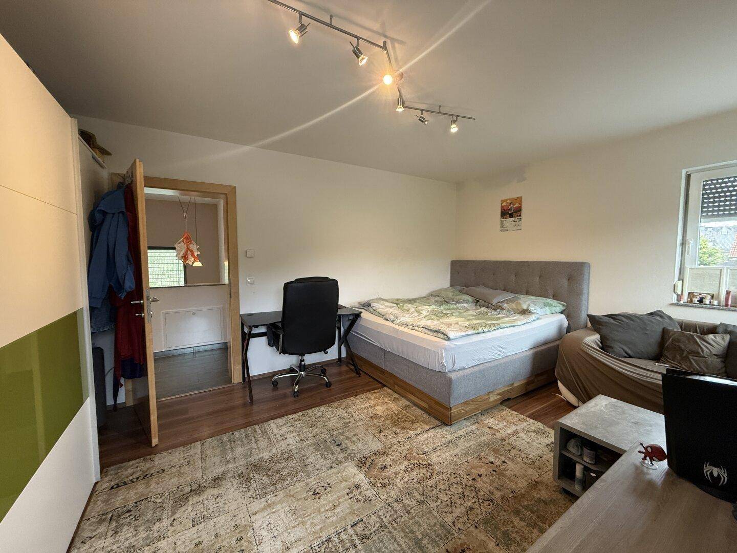 Schlafzimmer mit Bett, Schreibtisch und Sofa, ideal als Gäste- oder Arbeitszimmer.