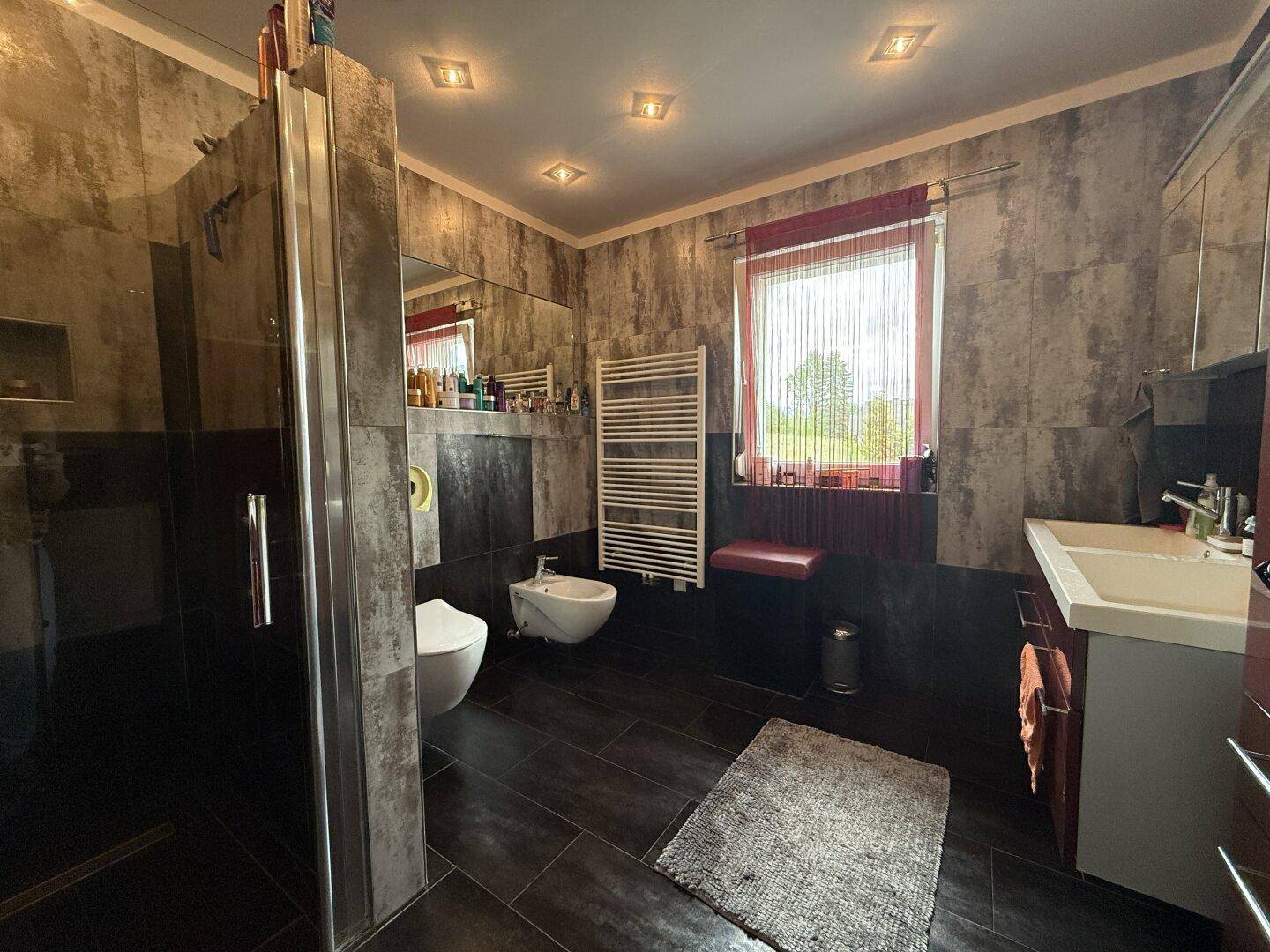 Modernes Badezimmer mit großer Dusche, Bidet und beheiztem Handtuchhalter.