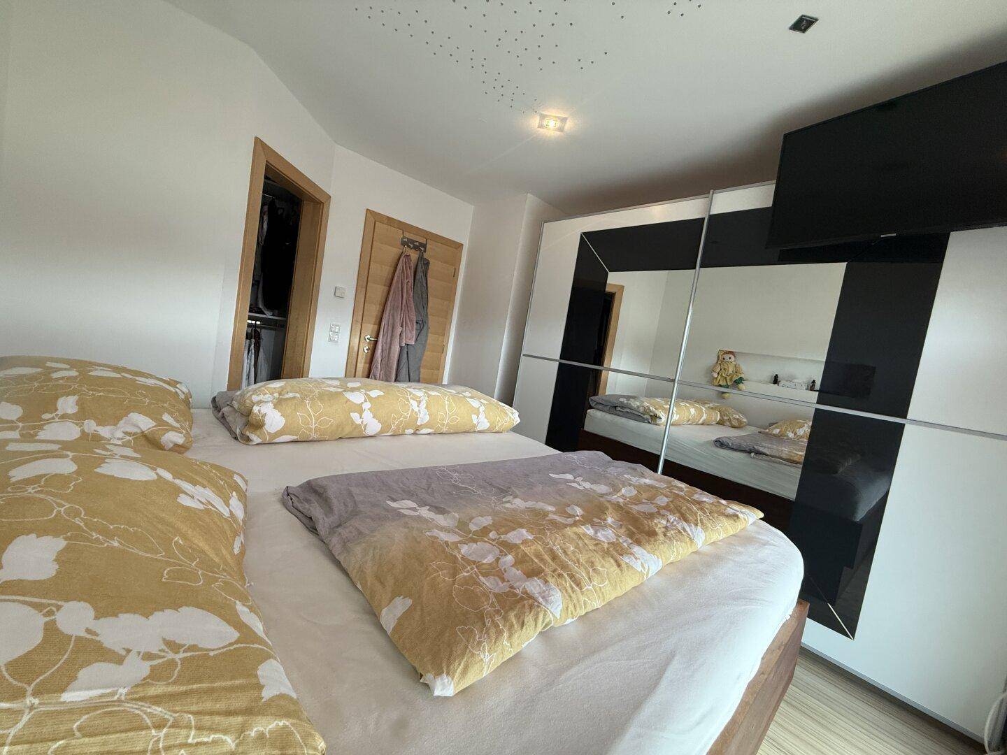 Gemütliches Schlafzimmer mit großem Bett und modernem Spiegelschrank.