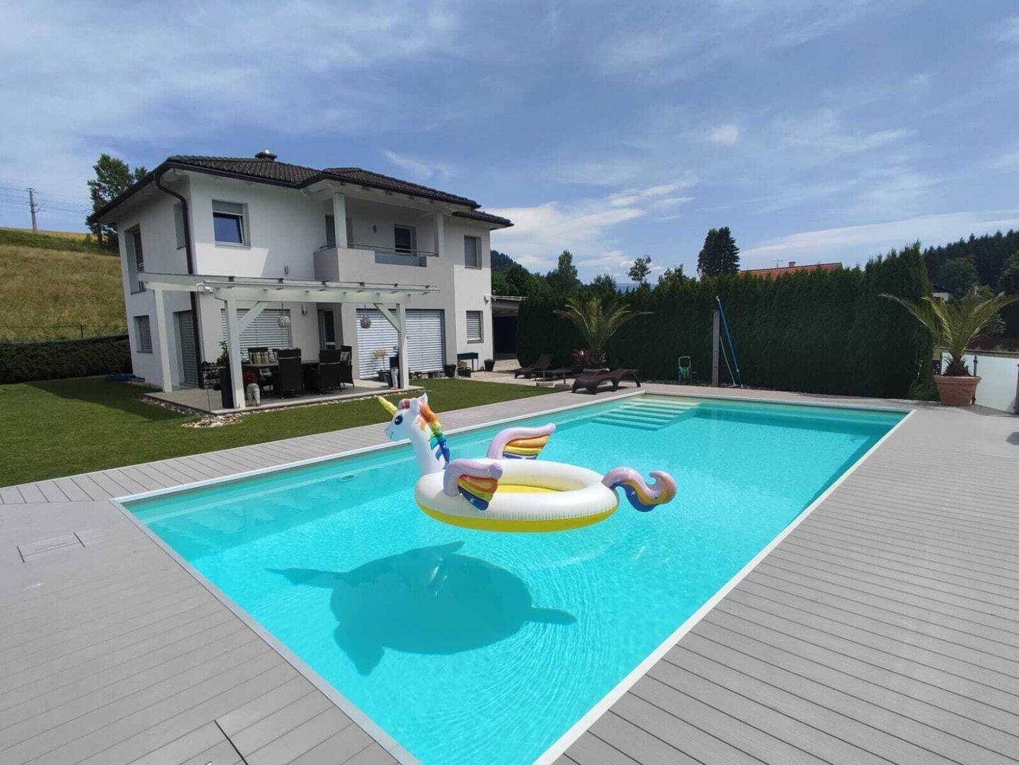 Sonniger Garten mit großem Swimmingpool und einer einladenden Liegewiese.