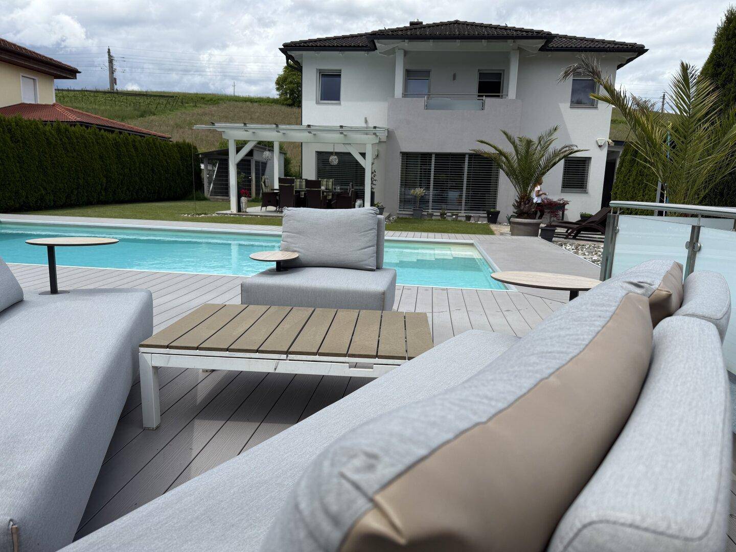 Entspannungsbereich im Garten mit bequemen Lounge-Möbeln und Blick auf den Pool.