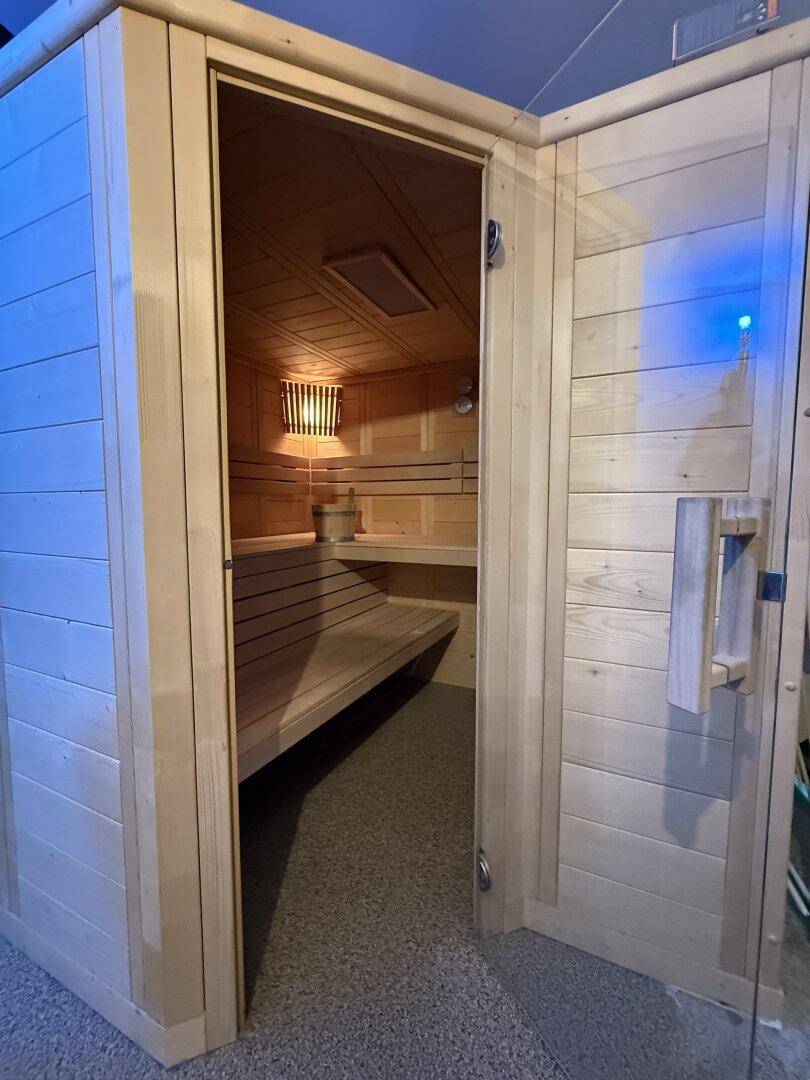 Gemütliche Holzsauna mit Sitzbänken und stimmungsvoller Beleuchtung für Entspannung.