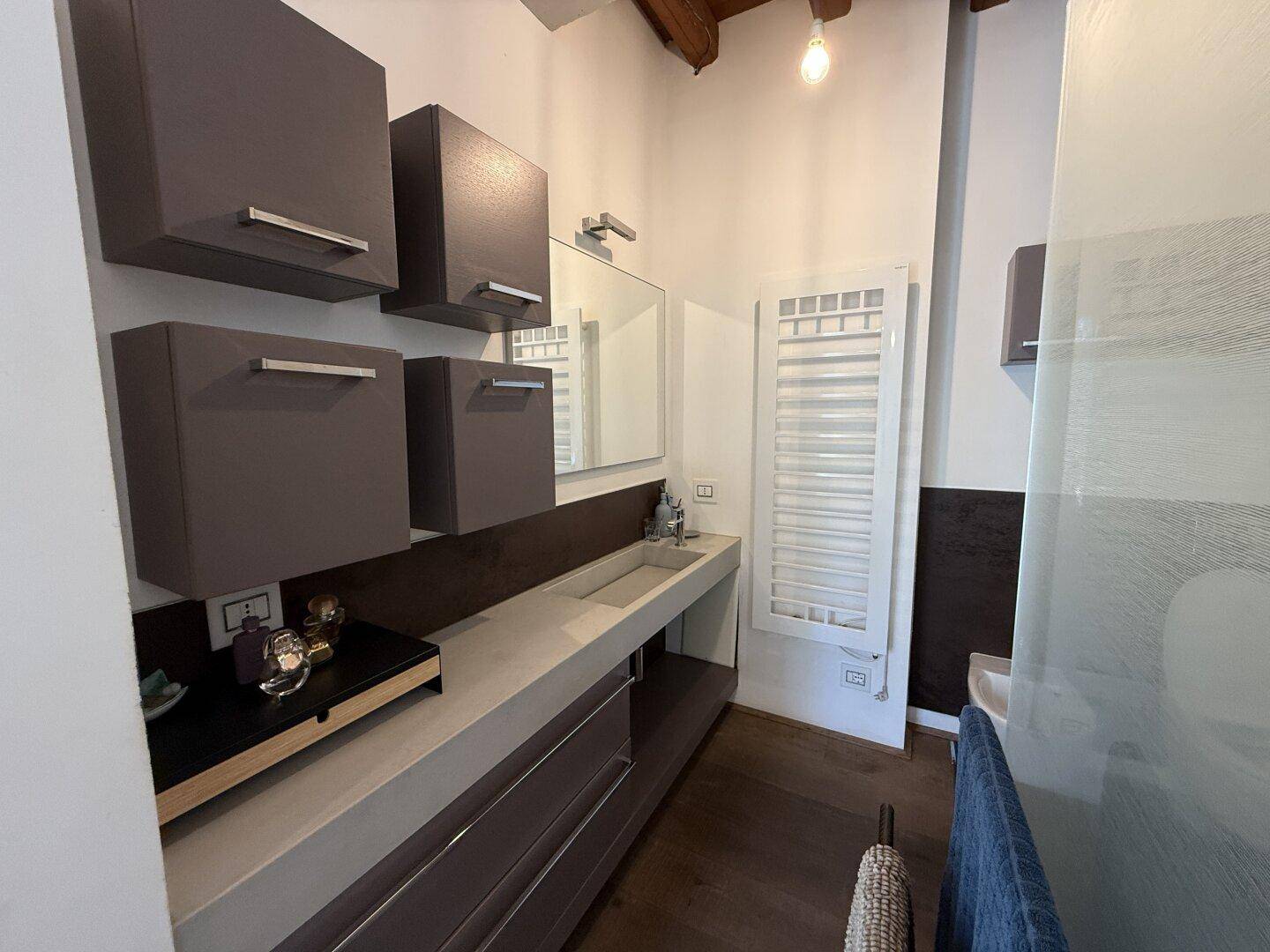Modernes Badezimmer mit schwebenden Schränken, einem einzelnen Waschbecken und beheiztem Handtuchhalter.