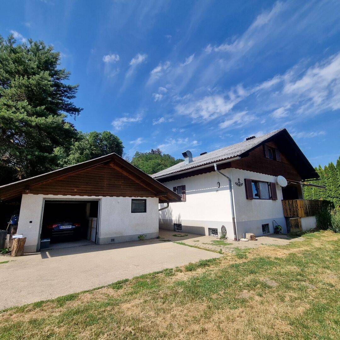 Einfamilienhaus mit angrenzender Garage und grünem Vorgarten unter strahlend blauem Himmel.