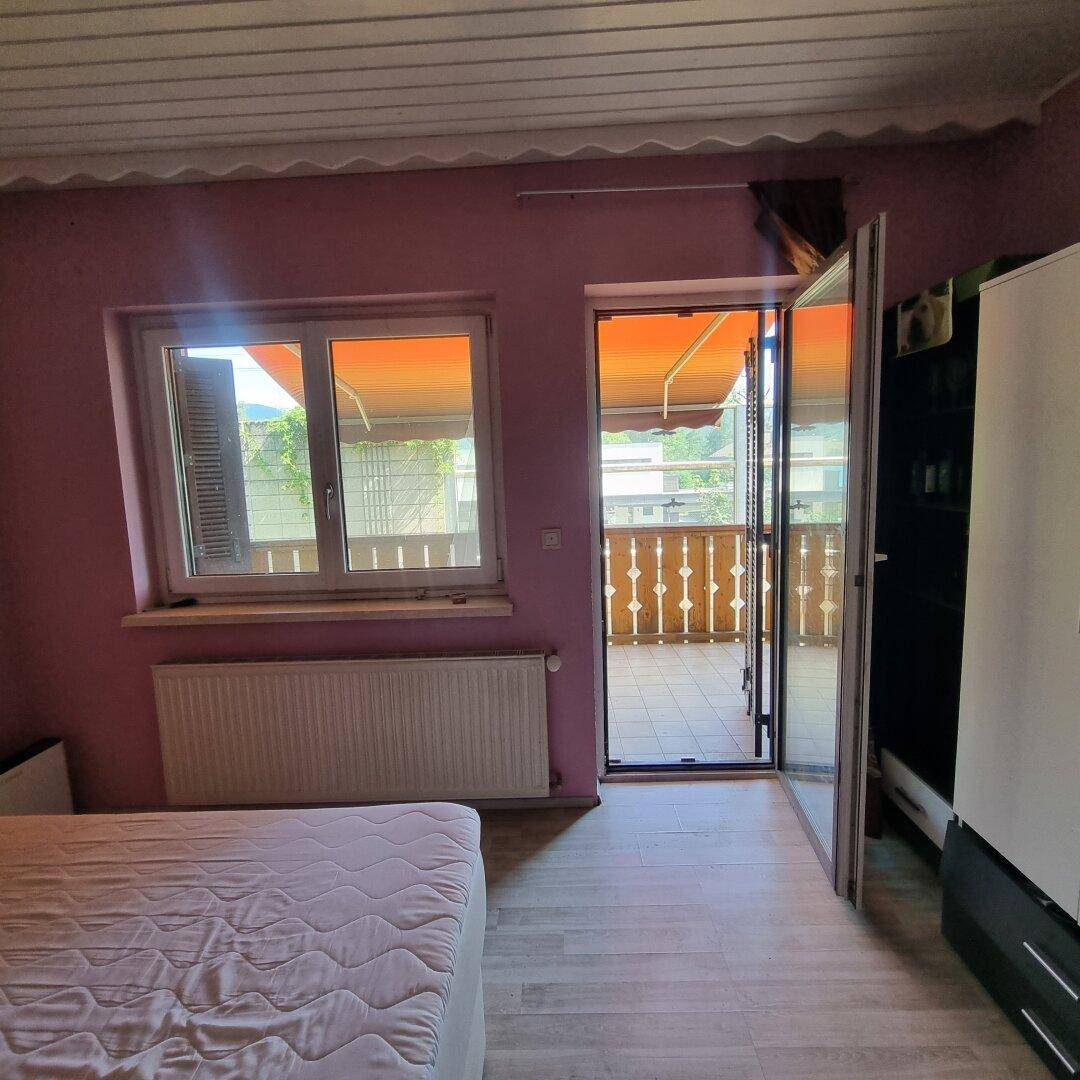 Schlafzimmer mit rosa Wänden, Heizkörper und direktem Zugang zum Balkon.