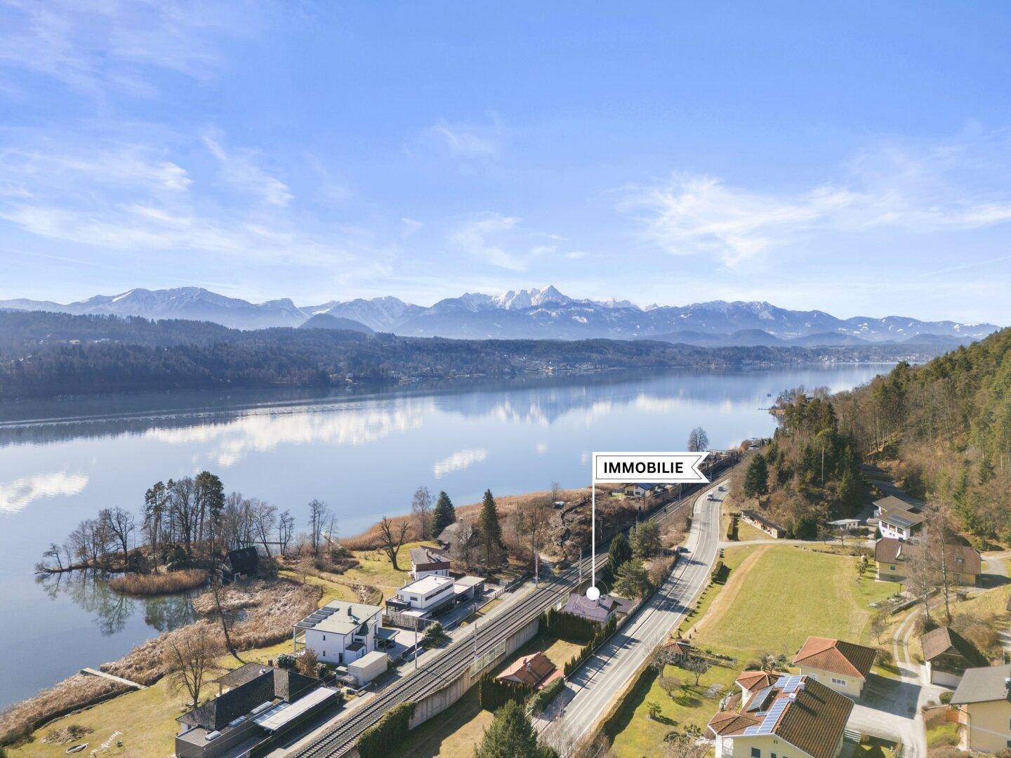 Luftaufnahme der Immobilie am Seeufer mit Bergpanorama und Lagekennzeichnung der Immobilie.