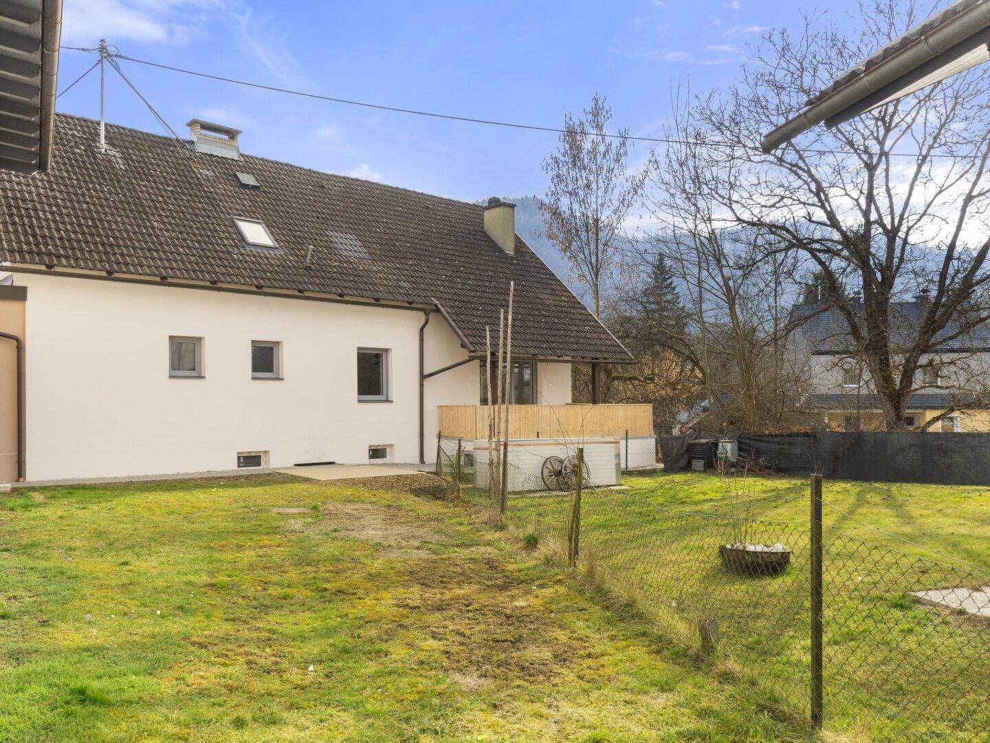 Hinterhof mit Rasenfläche und Blick auf die umliegende Berglandschaft und Nachbarhäuser.