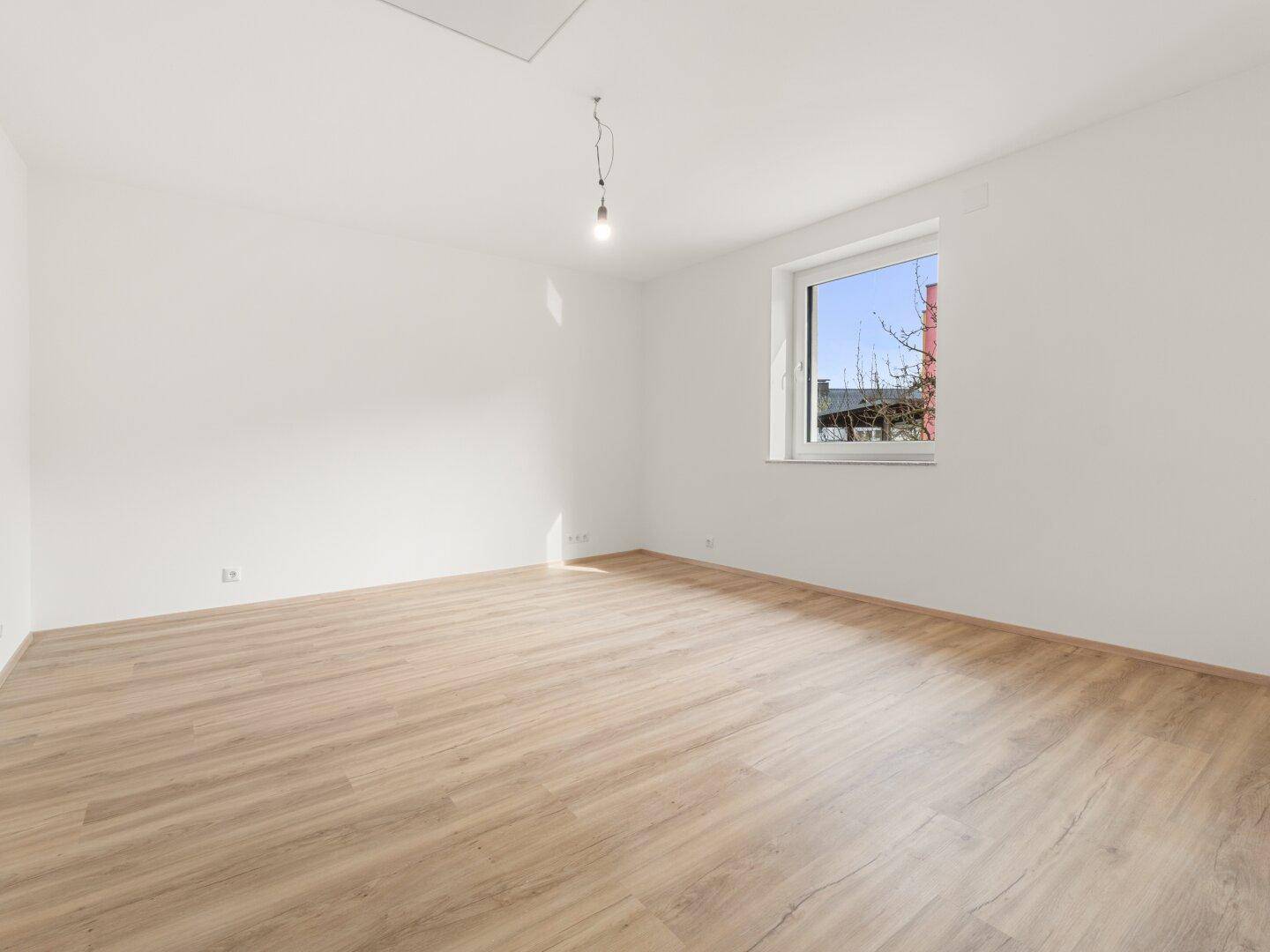 Helles Schlafzimmer mit Laminatboden, weißen Wänden und einem großen Fenster für viel Licht.