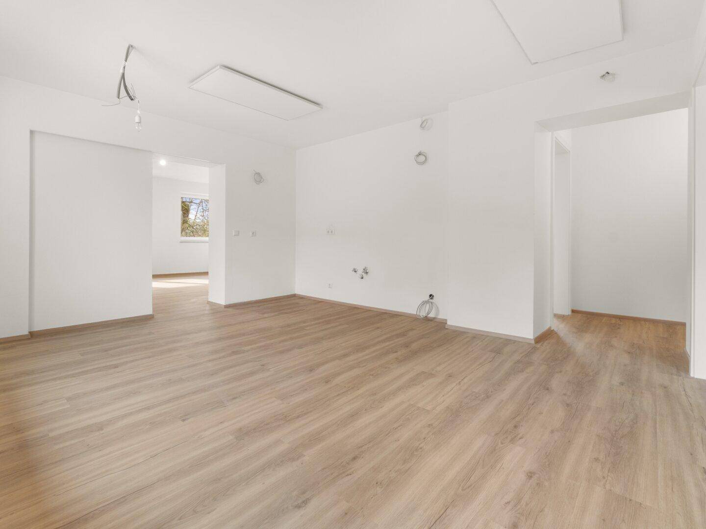 Offener Küchenbereich mit Laminatboden und Anschlüssen für die zukünftige Kücheninstallation.