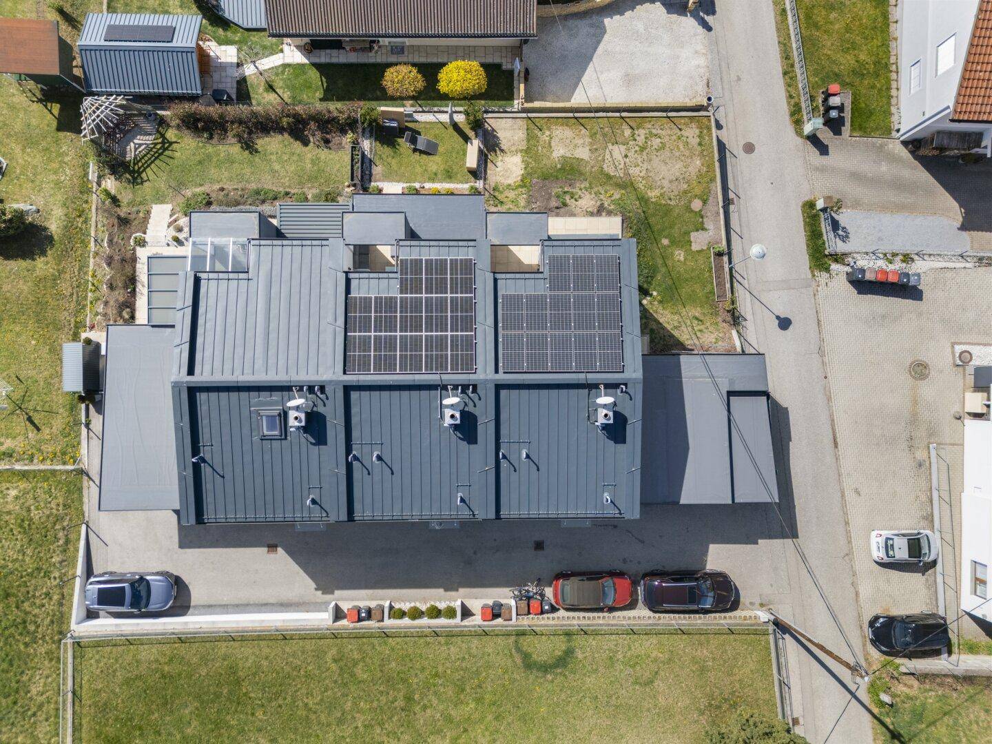 Dachansicht eines modernen Gebäudekomplexes mit mehreren Photovoltaikanlagen auf den Flachdächern.