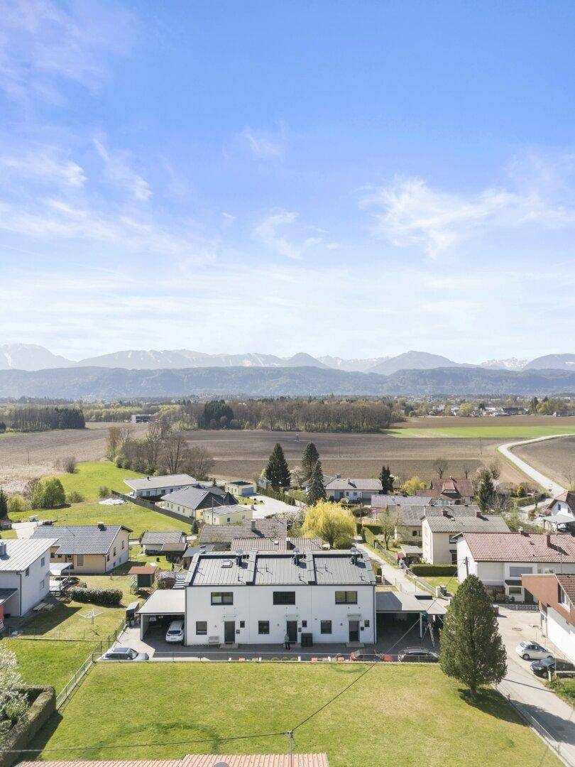 Luftaufnahme eines modernen Hauses mit großem Garten und Bergblick in ländlicher Umgebung.