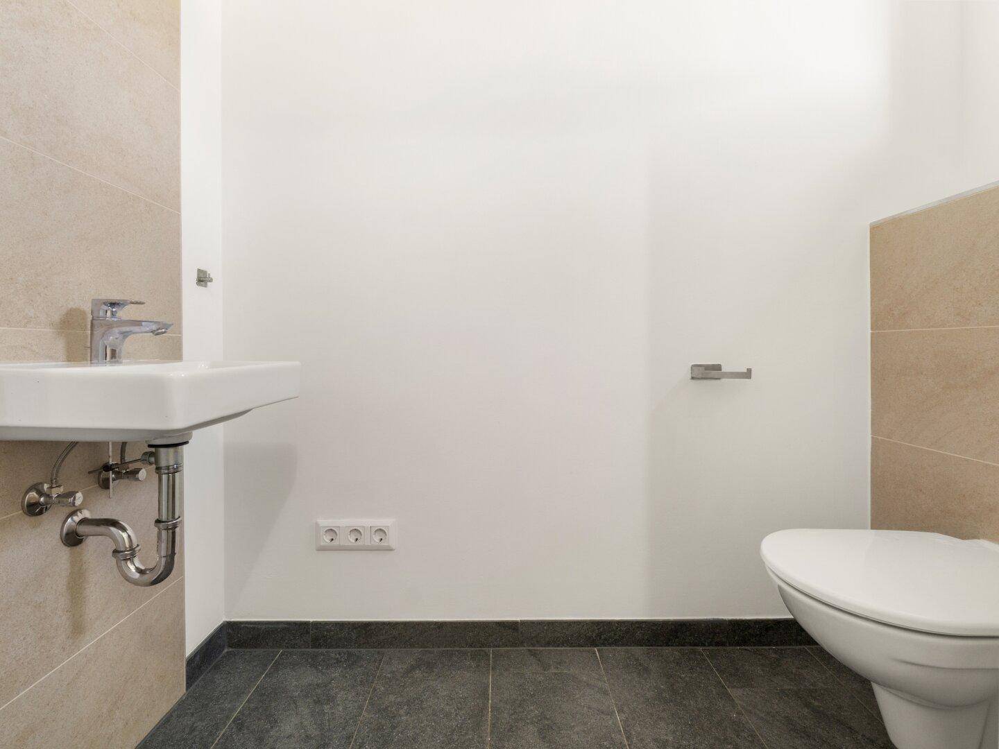 Helles Gäste-WC mit modernen Fliesen und minimalistischem Design.