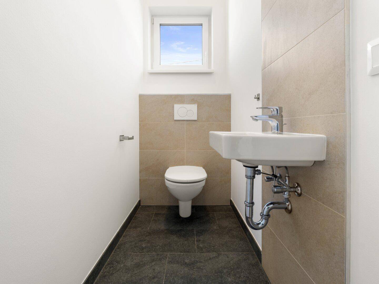 Modernes Gäste-WC mit wandhängender Toilette, kleinem Waschbecken und Fenster.
