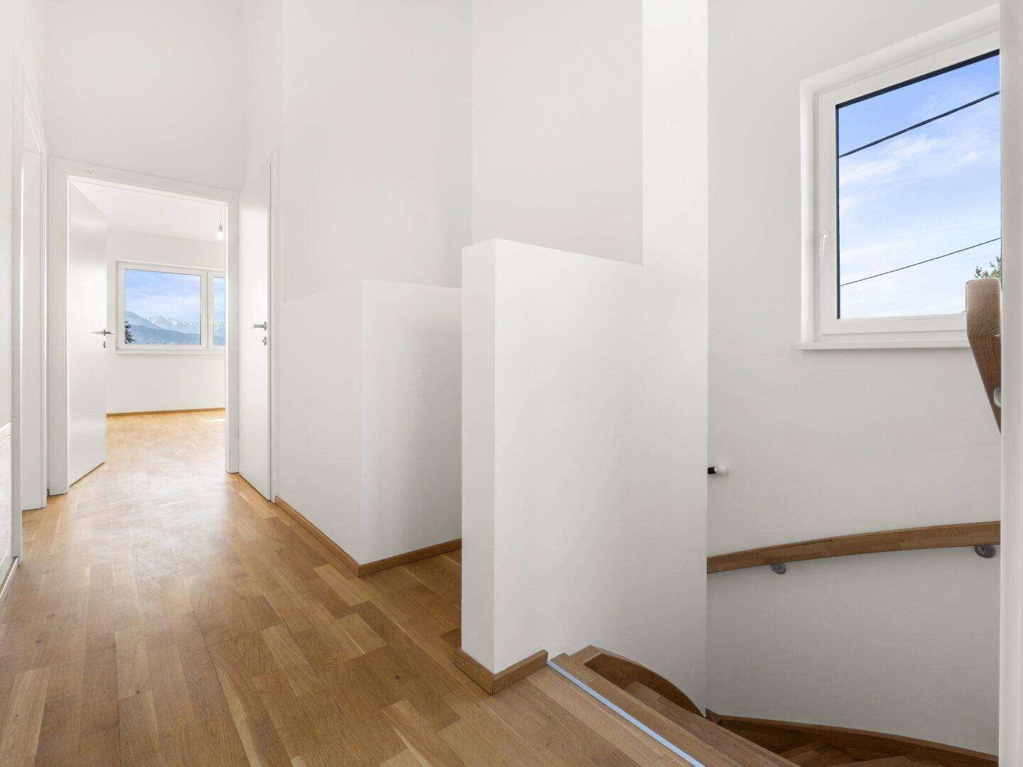 Heller Flur mit Holzparkettboden und Zugang zu weiteren Räumen sowie einer Holztreppe.