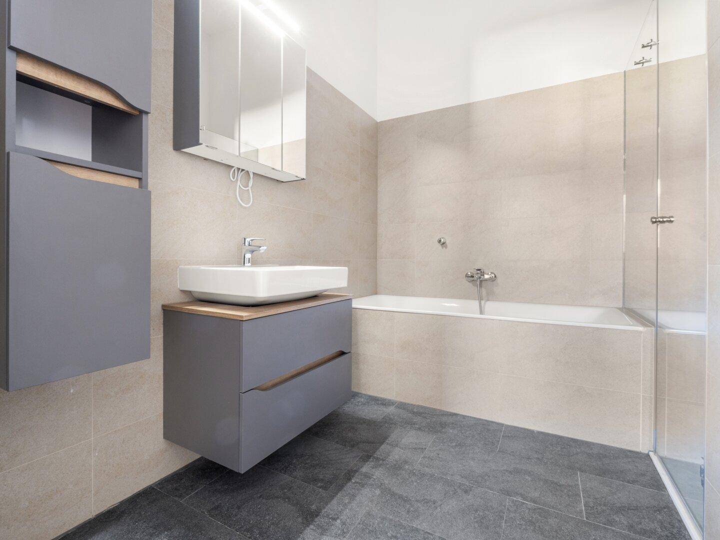Modernes Badezimmer mit Badewanne, Waschtischunterschrank und Spiegelschrank.