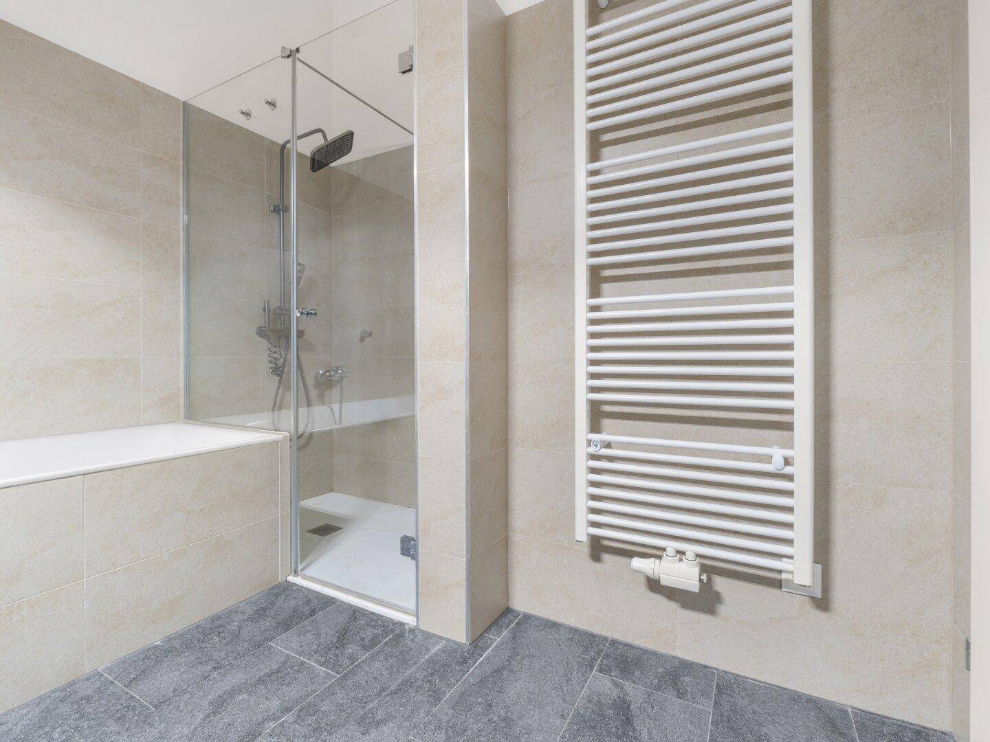 Modernes Badezimmer mit ebenerdiger Dusche, Badewanne und beheiztem Handtuchhalter.