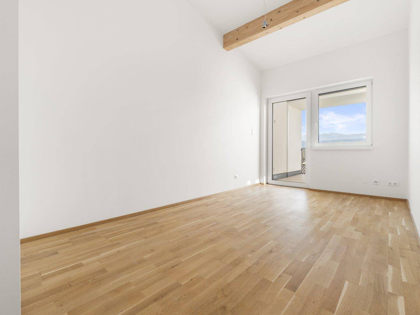 Lichtdurchflutetes Zimmer mit Zugang zu einem Balkon und weitem Bergblick.
