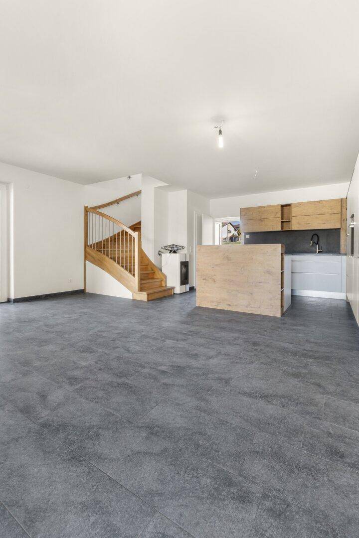 Geräumiger offener Wohn- und Essbereich mit integrierter Küche und Holztreppe.