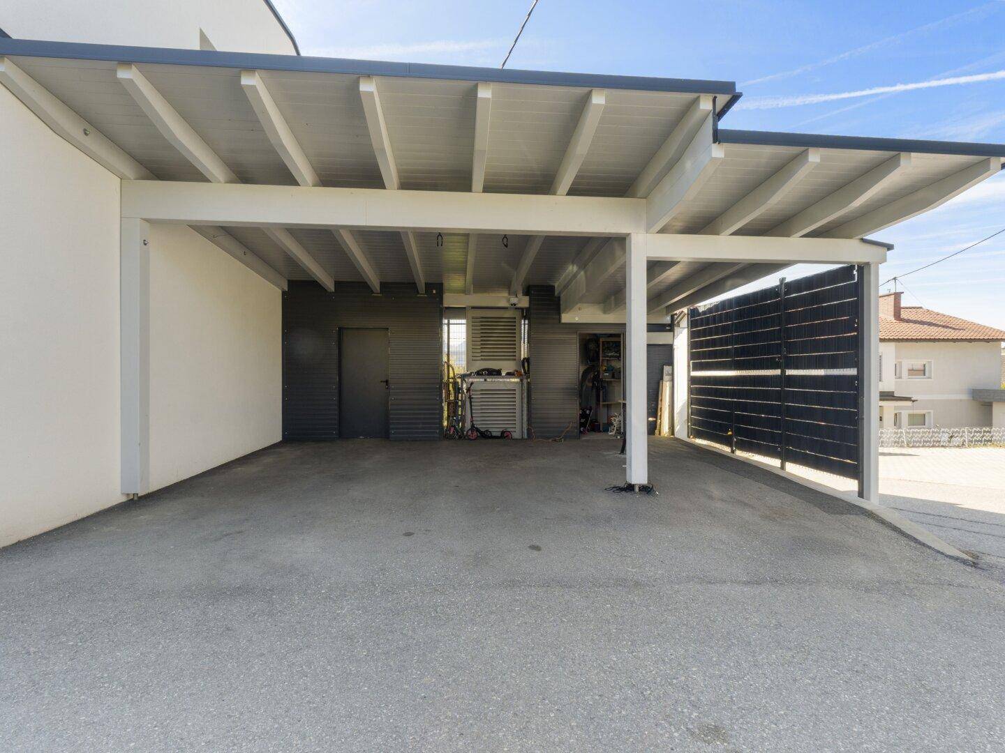 Geräumiger Carportbereich mit überdachten Stellplätzen und angrenzendem Abstellraum.