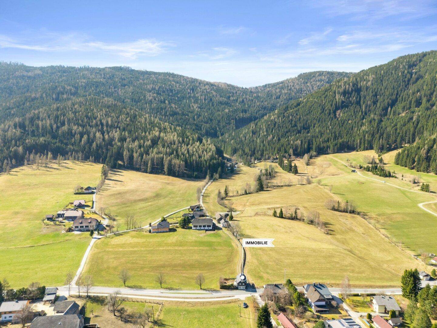 Luftaufnahme der ländlichen Umgebung mit weiten Feldern und bewaldeten Hügeln, Immobilienlage markiert.