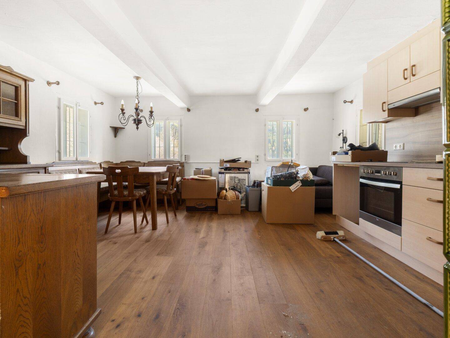 Geräumiger Wohn-Essbereich mit offener Küche, Holzboden und sichtbaren Deckenbalken.