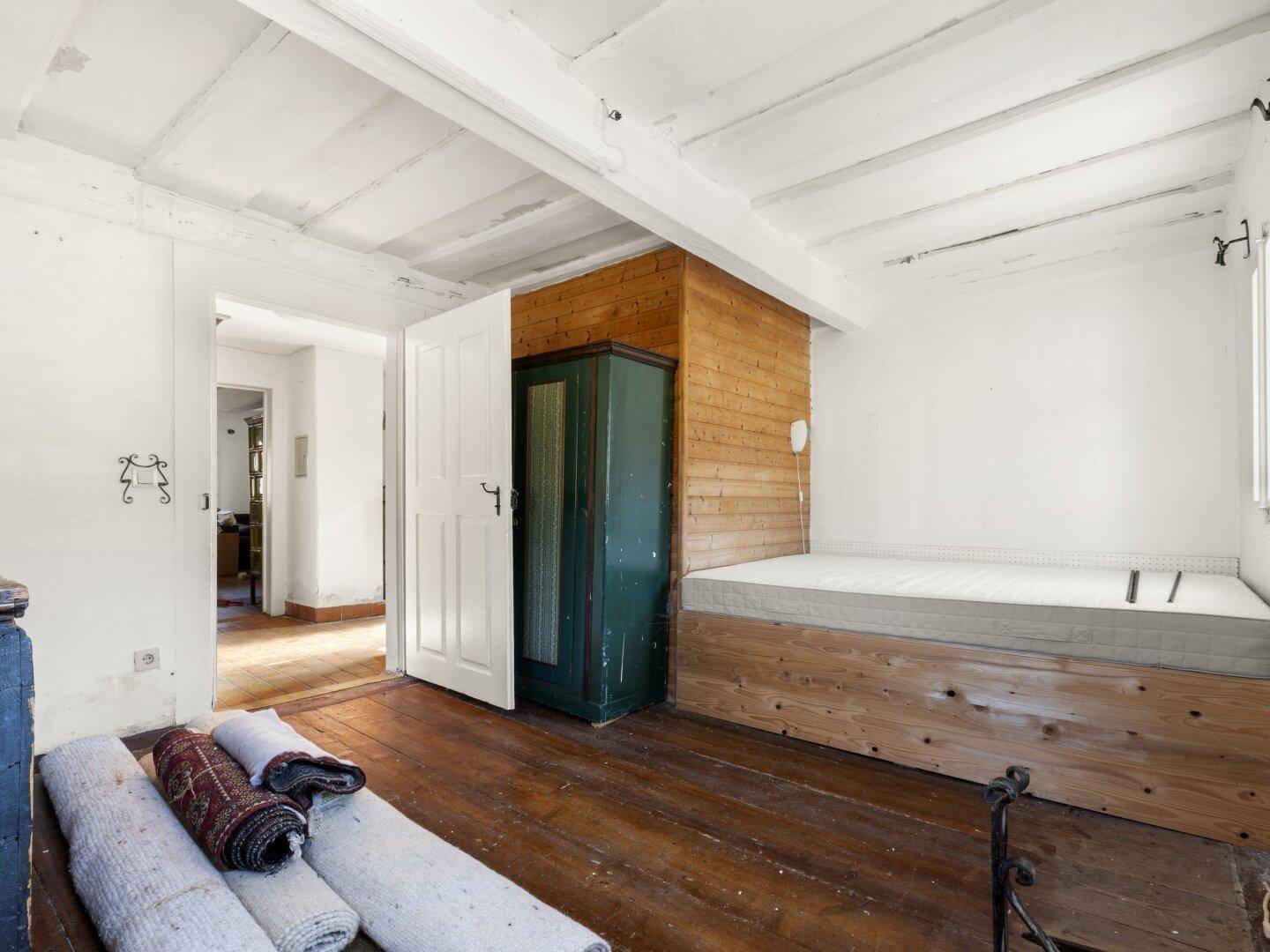 Schlafzimmer mit Holzboden, Holzvertäfelung und einem einfachen Holzbett, rustikaler Stil.