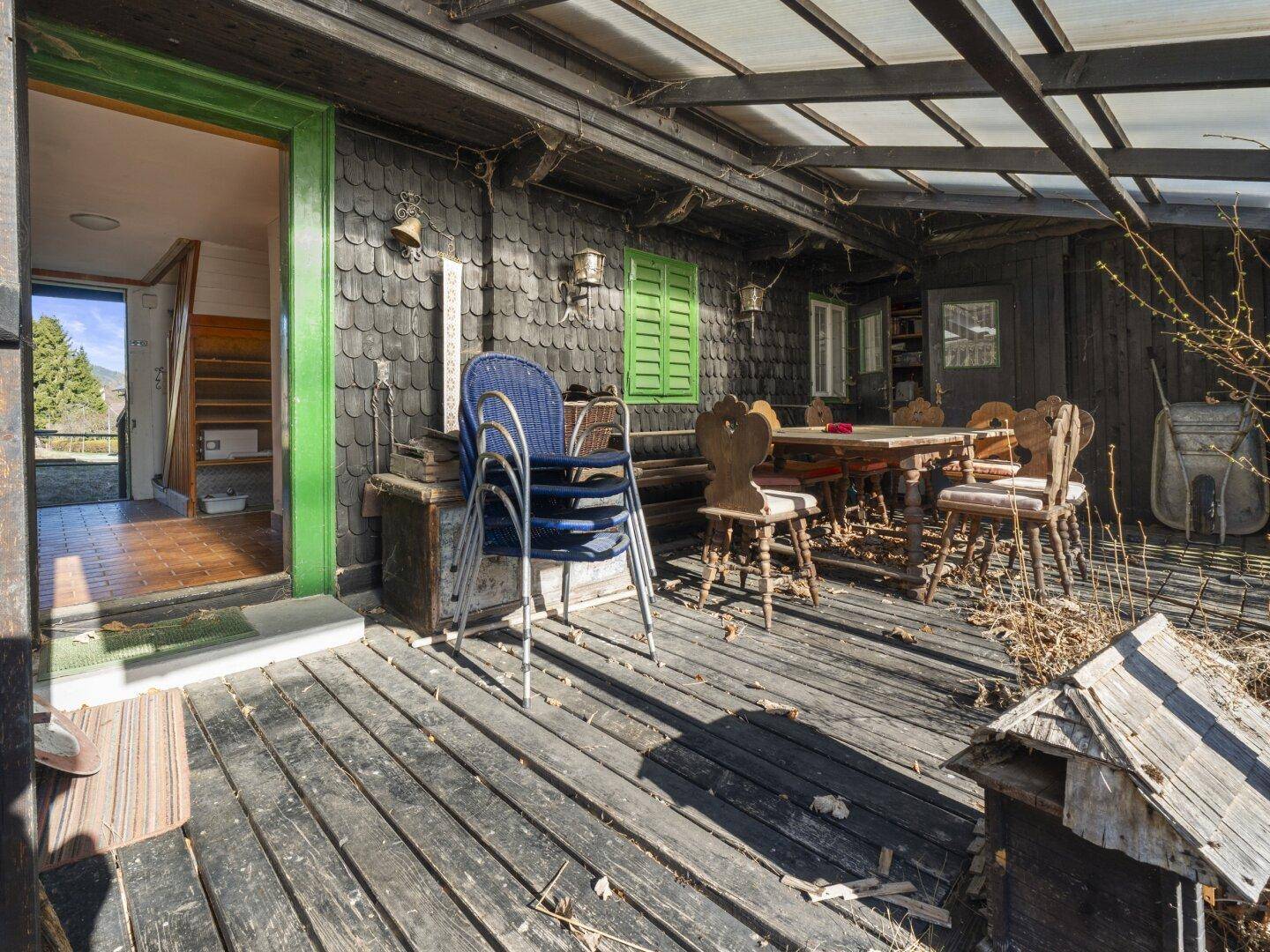 Überdachte Terrasse mit Holzboden und traditionellen Holzmöbeln, ideal für Mahlzeiten im Freien.
