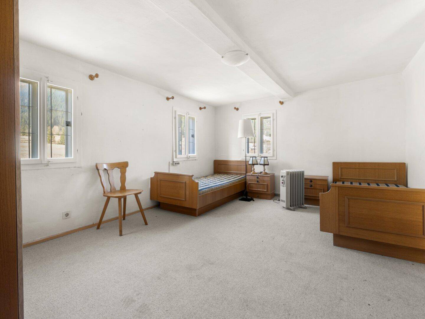 Helles Schlafzimmer mit Teppichboden, Holzbetten und mehreren Fenstern.