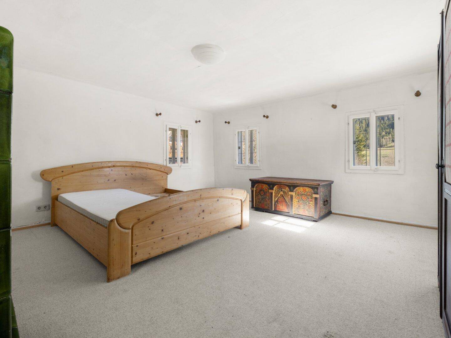 Geräumiges Schlafzimmer mit Teppichboden, Doppelbett und traditioneller Holztruhe.