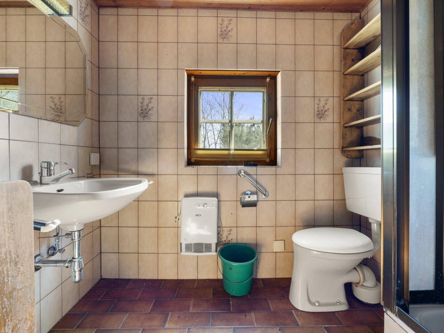 Badezimmer mit Fliesenboden, Waschbecken, Toilette und Fenster, einfacher Standard.