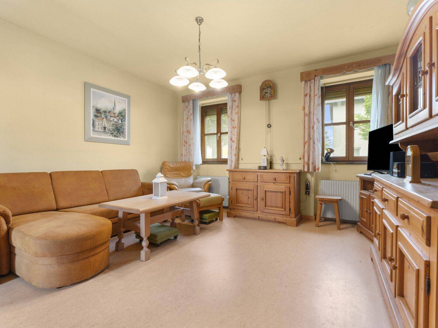 Geräumiges Wohnzimmer mit beiger Couch, Holzmöbeln und gemütlicher Atmosphäre.