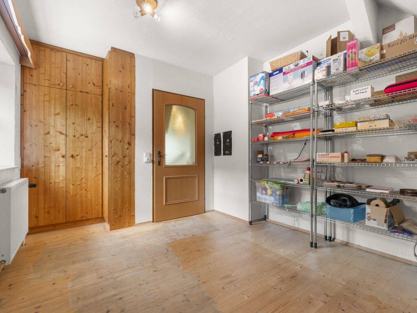 Praktischer Abstellraum mit Holzschrank, Regalen und Holzboden für zusätzlichen Stauraum.