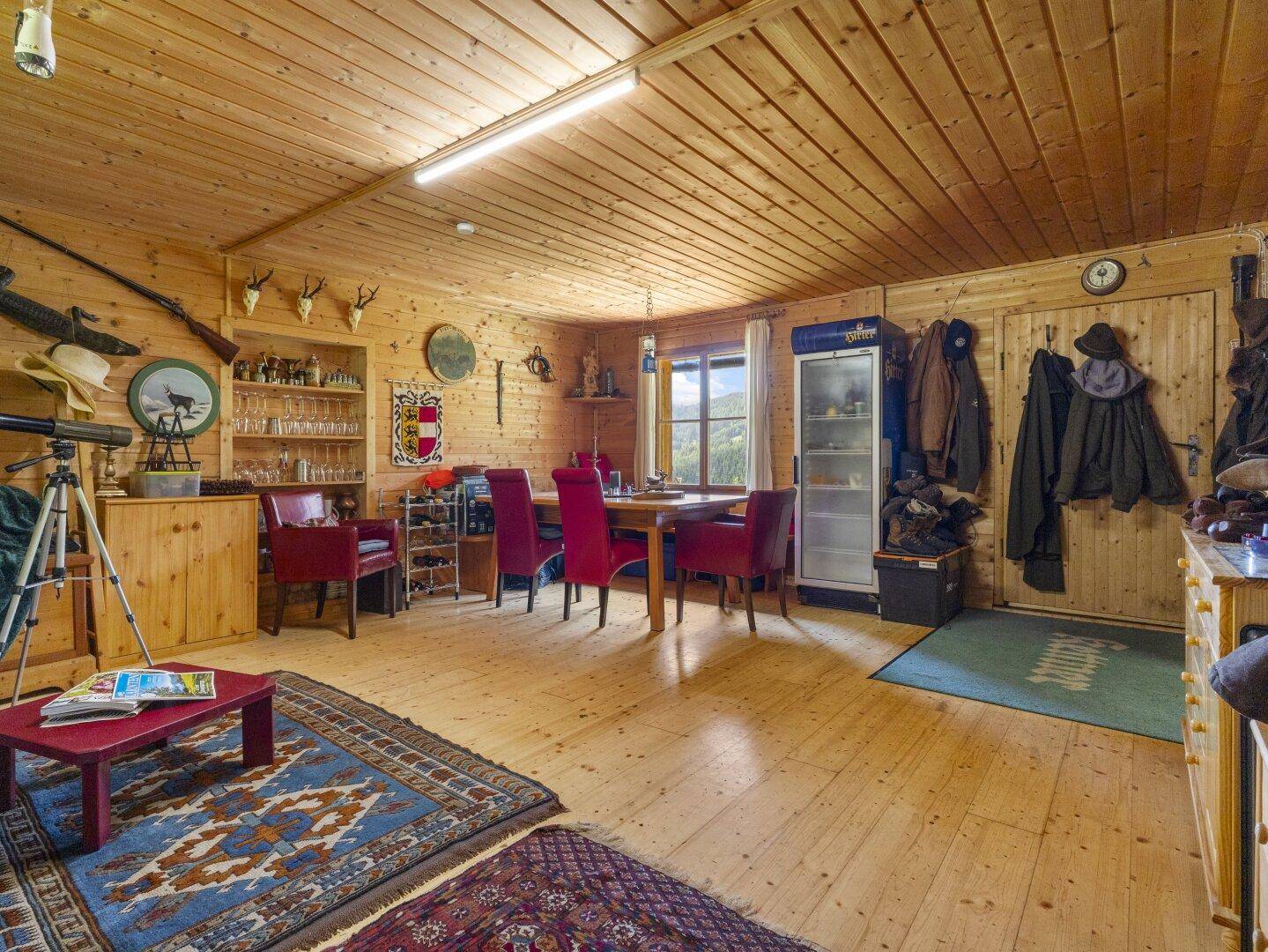 Geräumiger Wohn- und Essbereich im alpinen Stil mit Holzwänden, Esstisch und Jagdtrophäen.