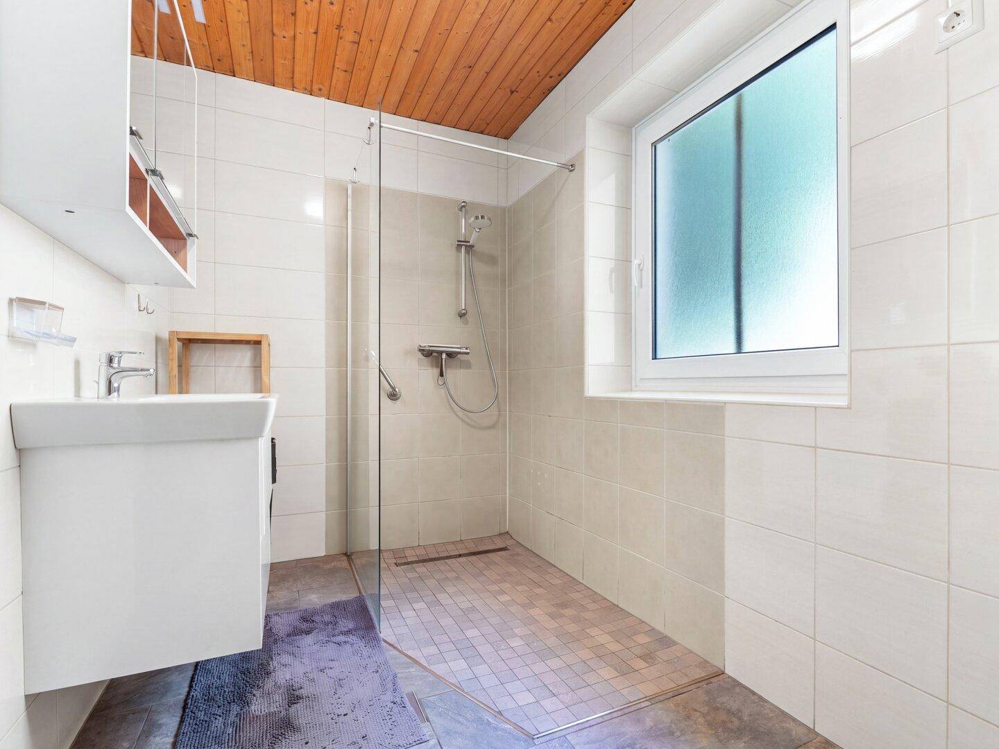 Modernes Badezimmer mit begehbarer Dusche, Fliesen und Holzdecke.