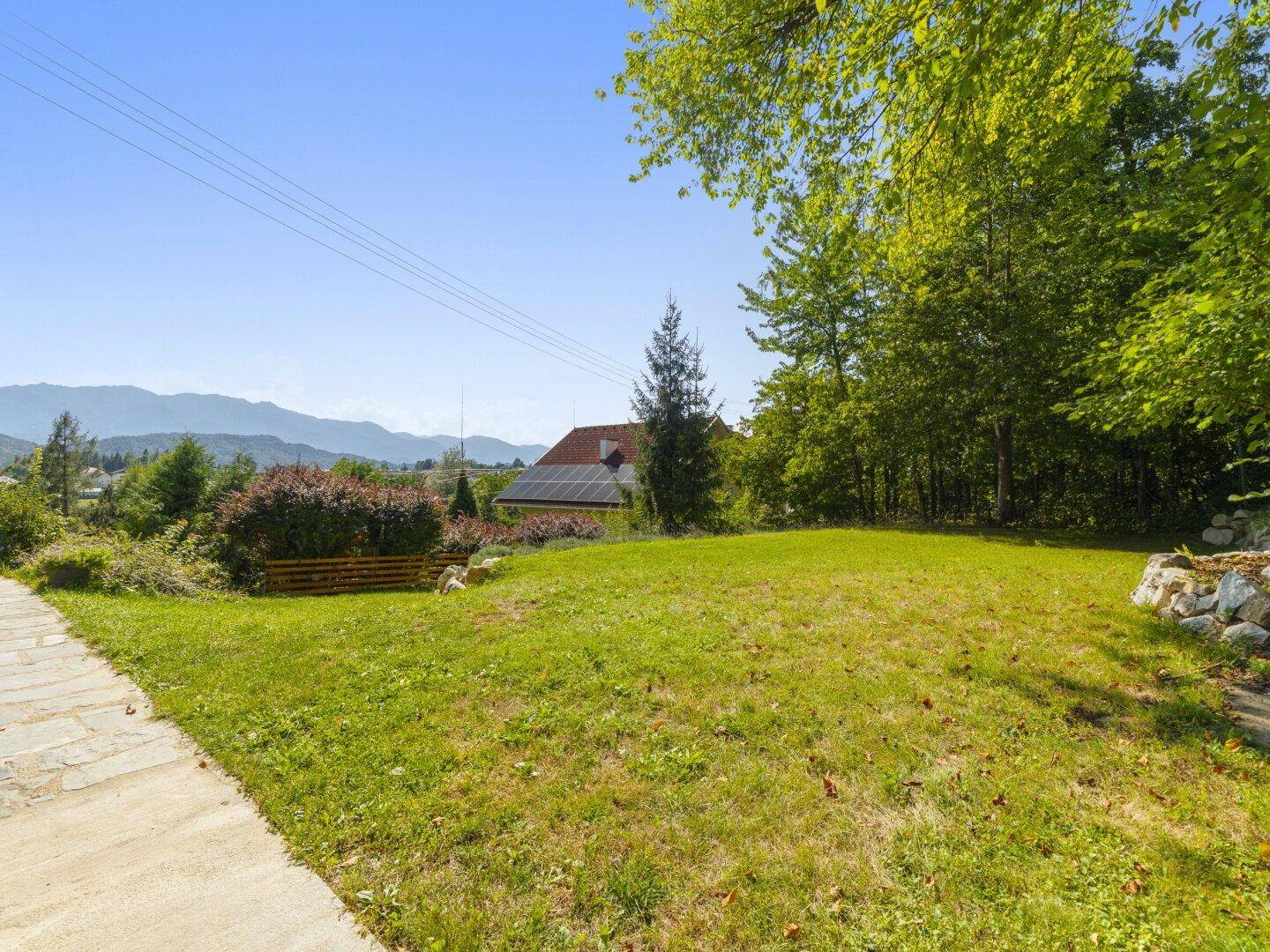 Weitläufige Rasenfläche des Gartens mit Blick auf die umliegende Berglandschaft.
