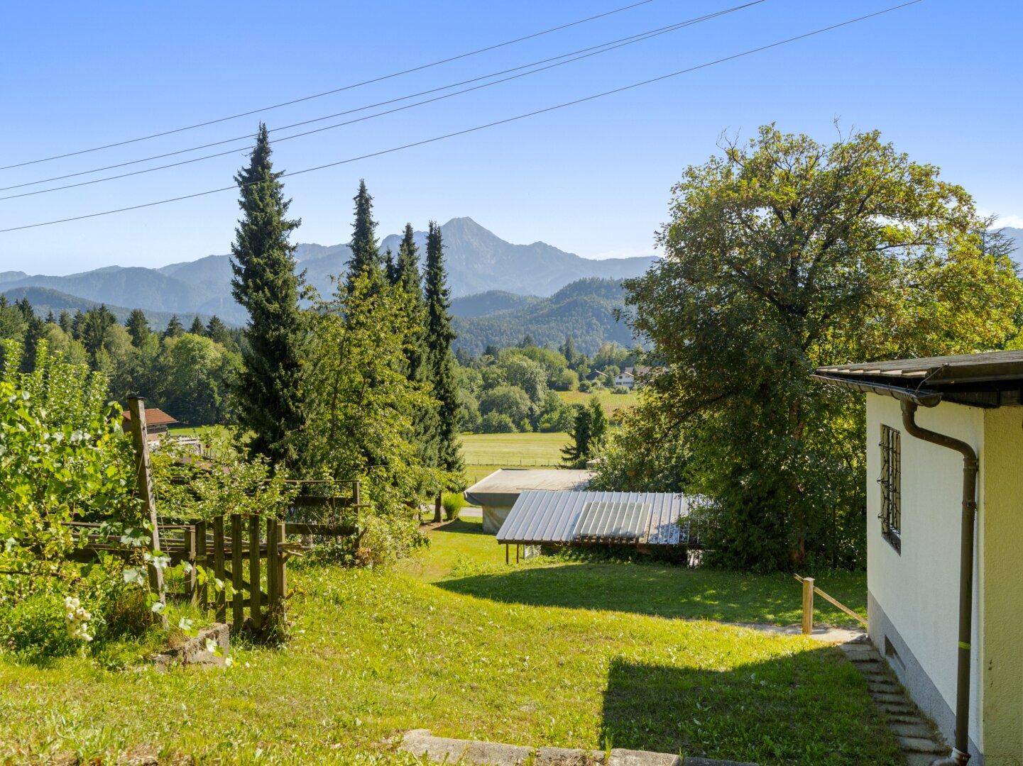 Grüner Gartenbereich mit Obstbäumen und weitem Blick auf die umliegende Berglandschaft.
