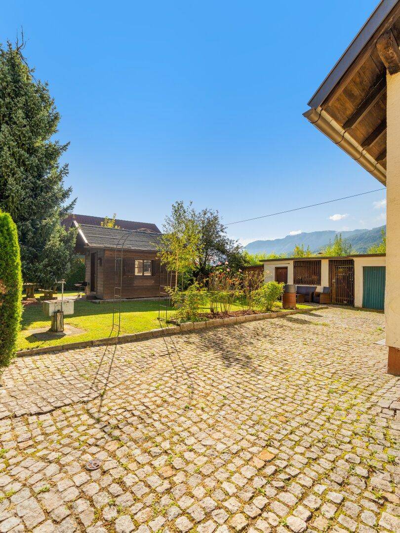 Gepflasterter Hofbereich mit Kopfsteinpflaster und einem charmanten Holzschuppen im Garten.