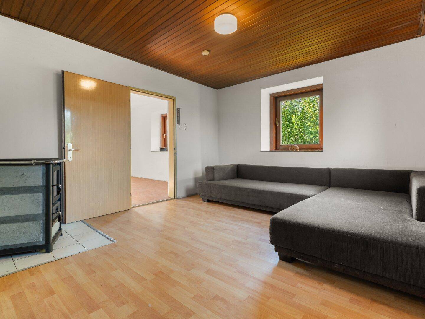 Gemütliches Wohnzimmer mit Holzbalkendecke, Laminatboden und einem bequemen Ecksofa.