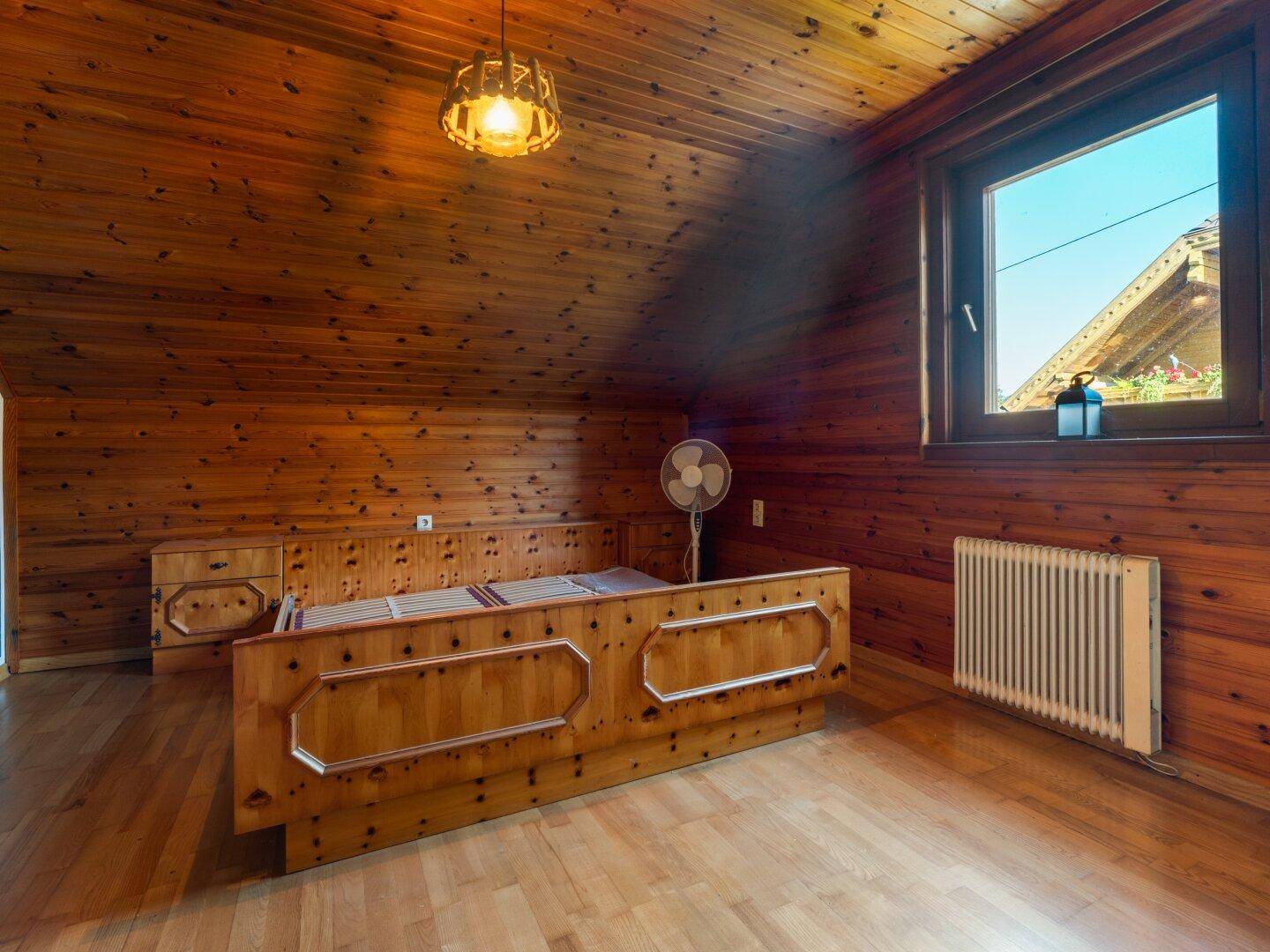 Rustikales Dachschlafzimmer mit Holztäfelung an Wänden und Decke sowie Holzboden.