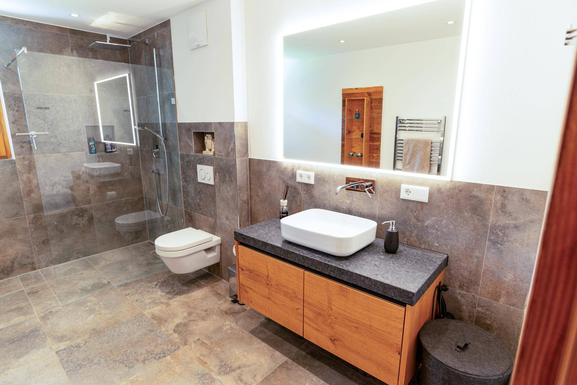 Elegantes Badezimmer mit großem Spiegel, Einzelwaschbecken und begehbarer Dusche.