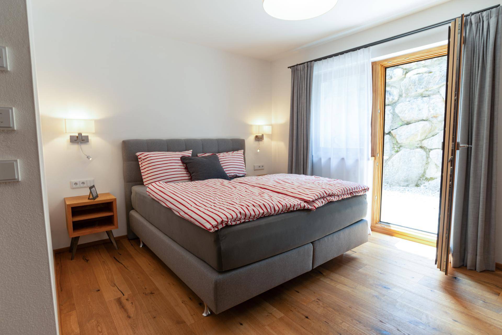 Gemütliches Schlafzimmer mit Holzboden, Doppelbett und Zugang zum Außenbereich.