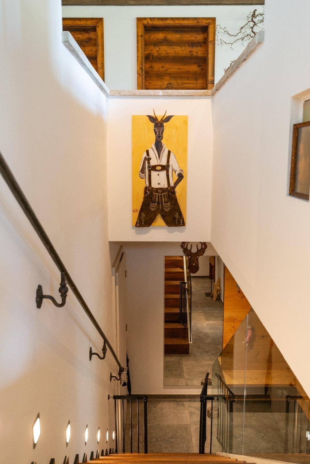 Treppenhaus mit Holzstufen, weiß gestrichenen Wänden und traditioneller Kunst.