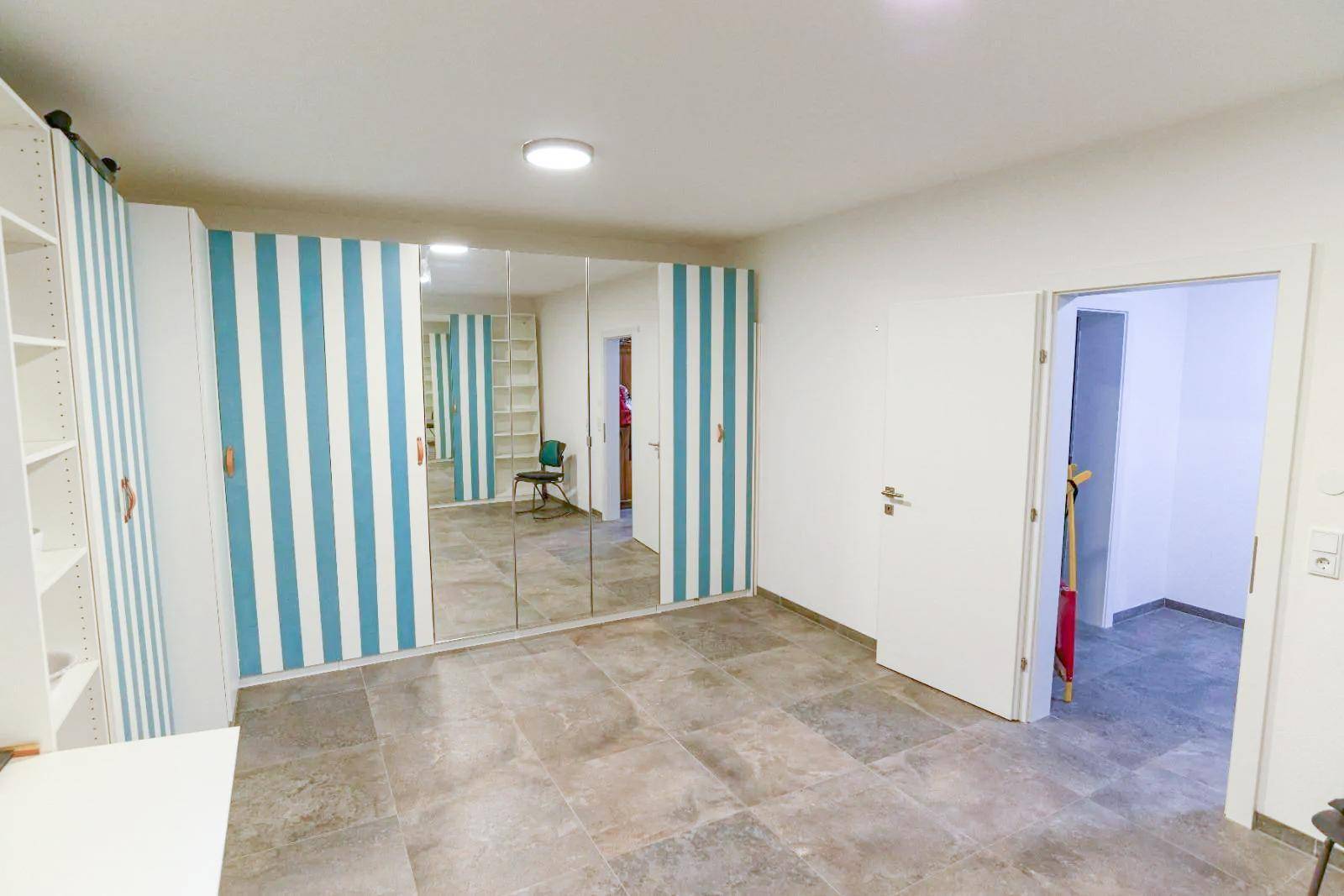 Geräumiges Zimmer mit Spiegelschränken und gestreifter Wanddekoration.