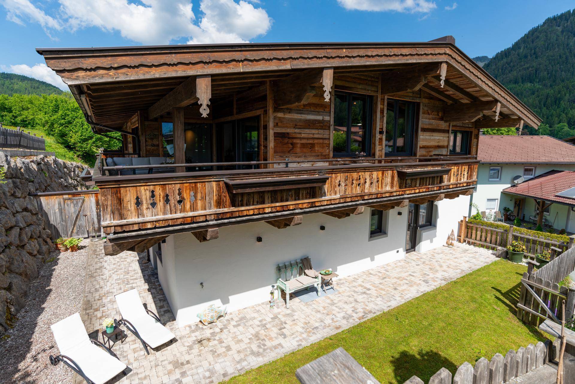 Charmantes Holzhaus mit gepflegtem Gartenbereich und gepflasterter Terrasse im alpinen Stil.