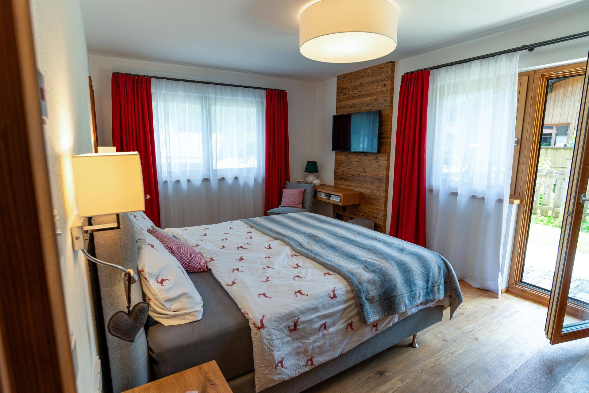 Helles Schlafzimmer mit Holzboden, Doppelbett und Zugang zum Balkon.