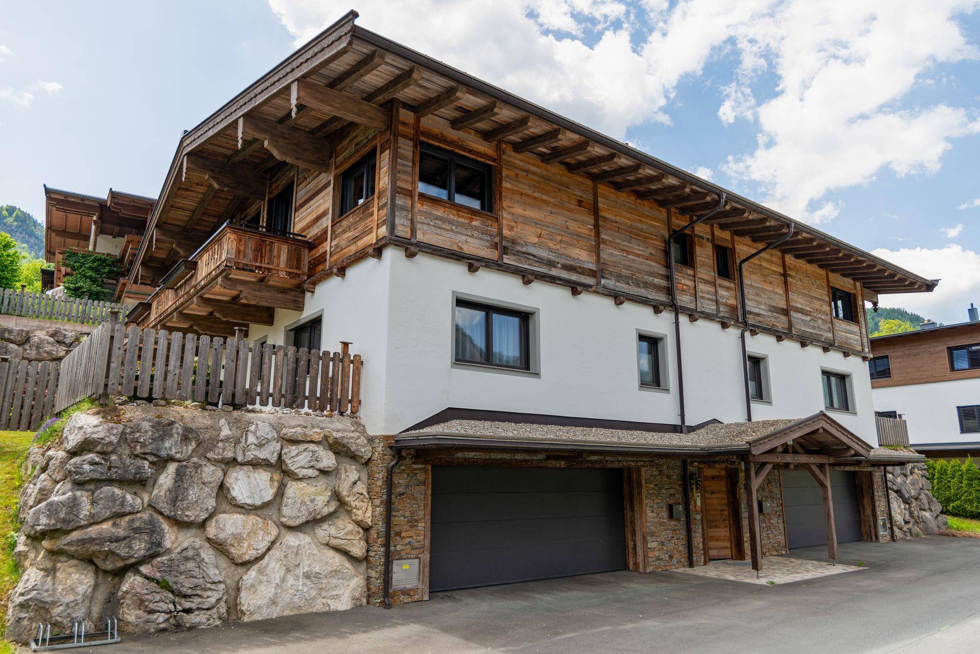 Alpines Gebäude mit Steinfassade, Garagen und traditioneller Holzverkleidung.
