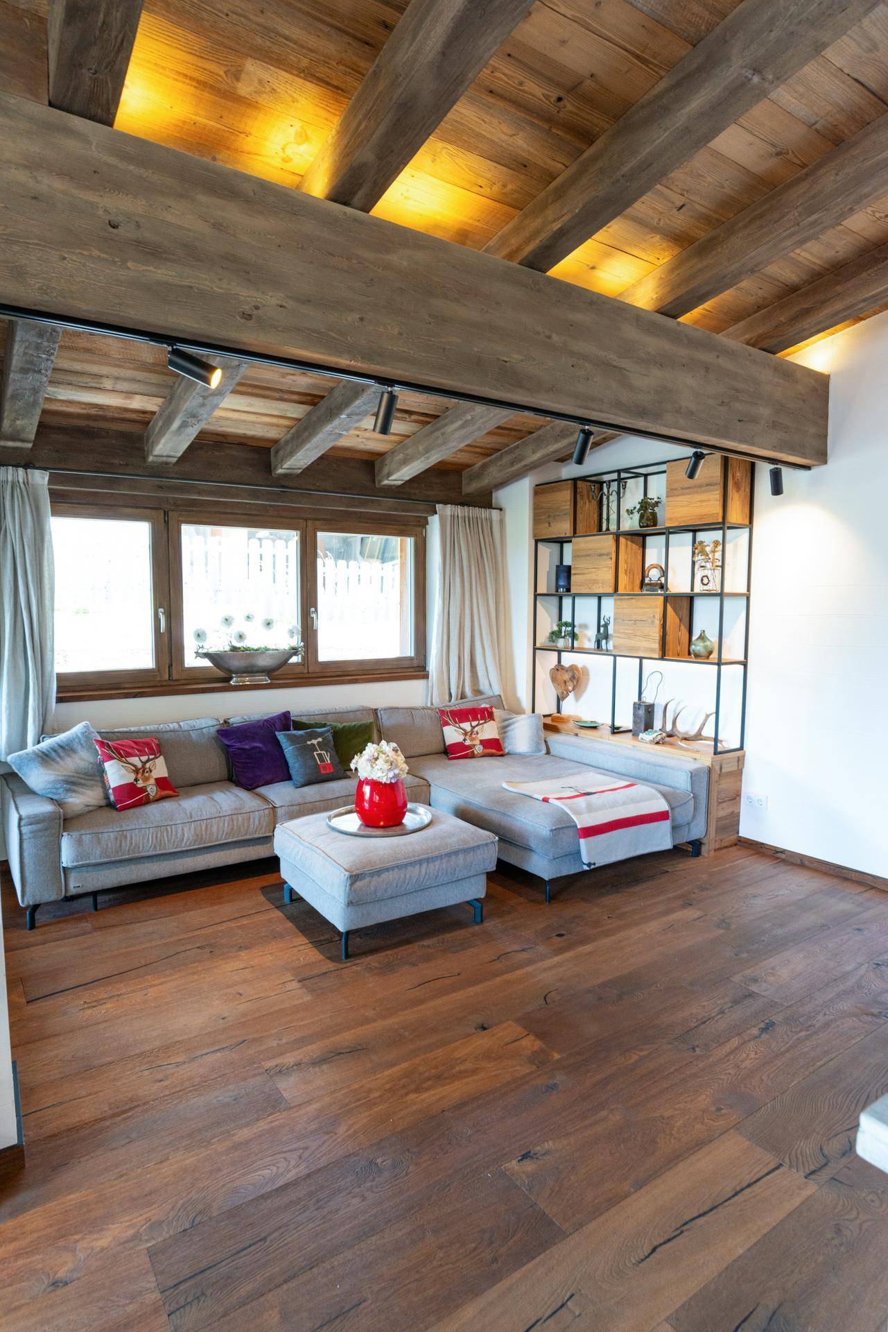 Geräumiges Wohnzimmer mit Holzboden, bequemer Couch und dekorativen Kissen.