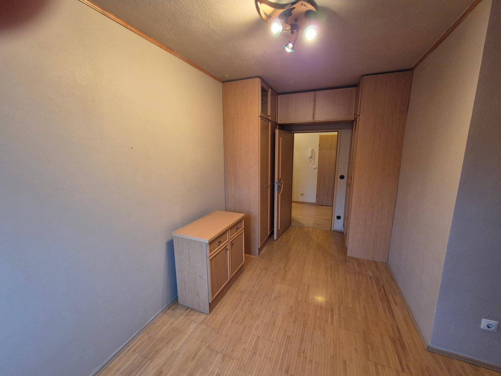 Schlafzimmer mit Parkettboden und einem Schrank, der in den Raum integriert ist.