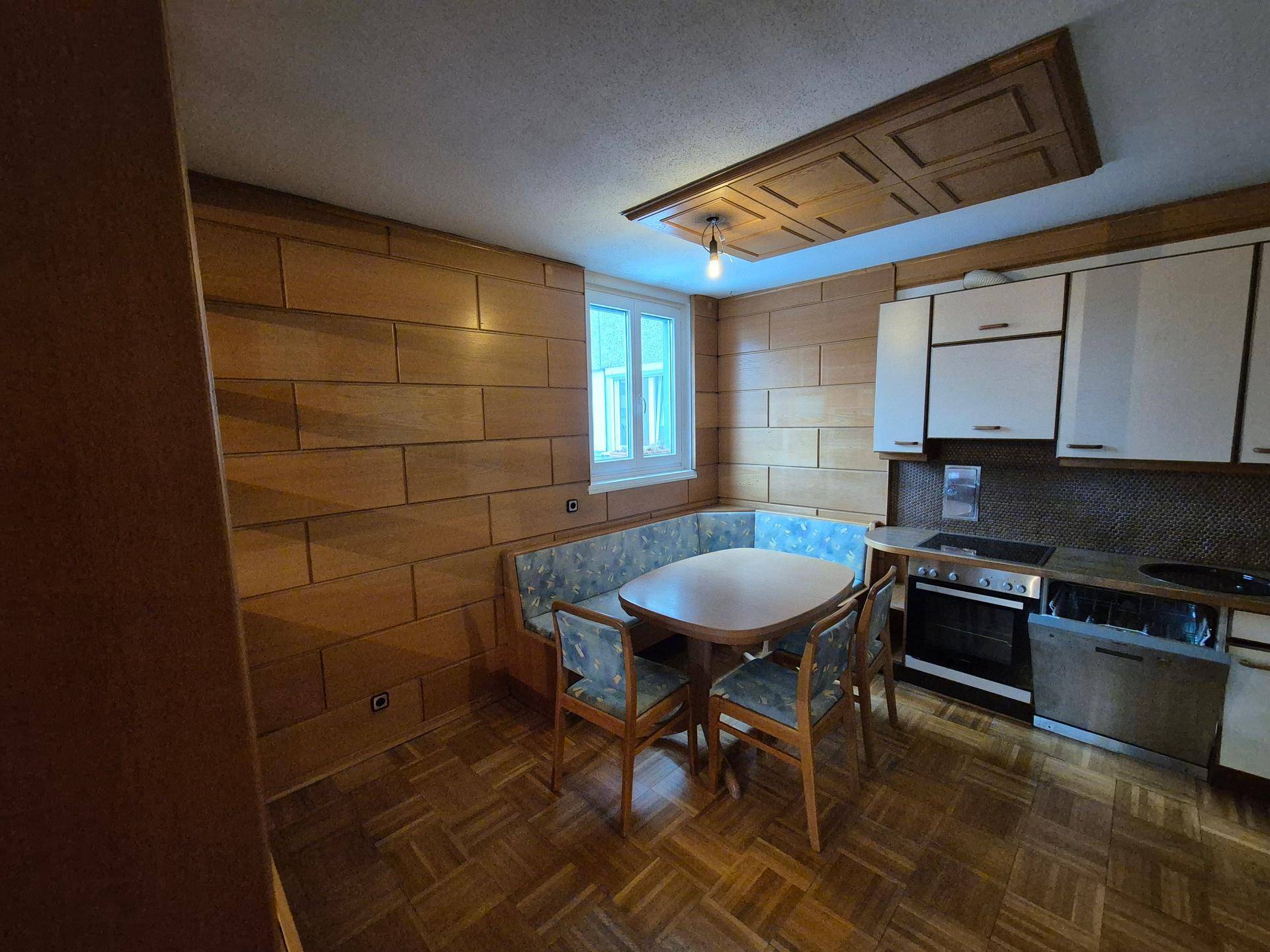 Wohnküche mit Essecke, Holzwandverkleidung und Einbauküche in traditionellem Stil.