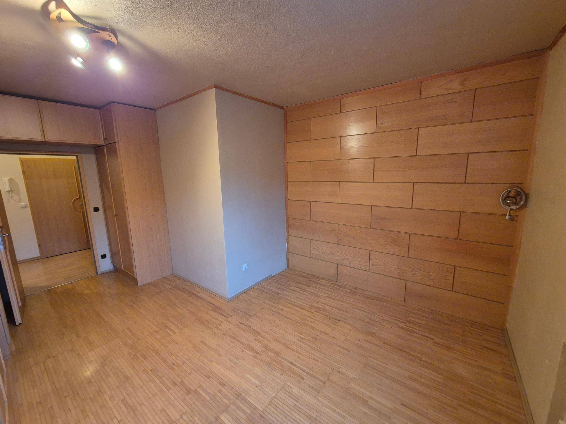 Schlafzimmer mit Holzwandverkleidung und Parkettboden, bereit für individuelle Gestaltung.